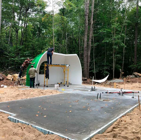 Concrete foundation and utility openings for Fern Hollow at a wooded Maine construction site.