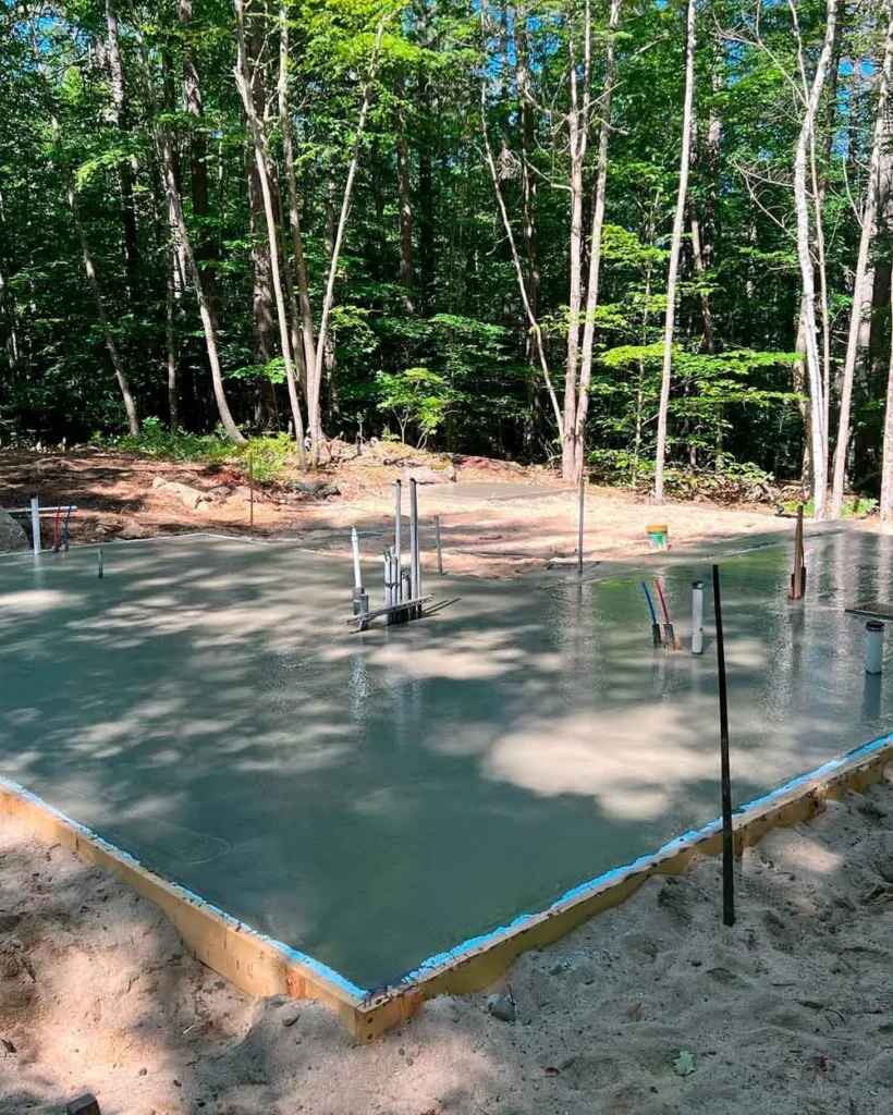 Concrete foundation and utility openings for The Shire hobbit house at a wooded Maine site.